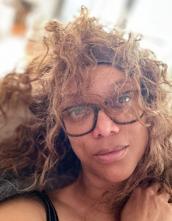 A woman with curly hair and glasses, showcasing a new look at a fashion gala.