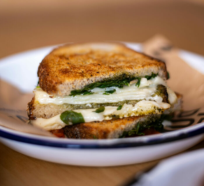 Grilled cheese sandwich on a plate with spinach and melted cheese in Europe.