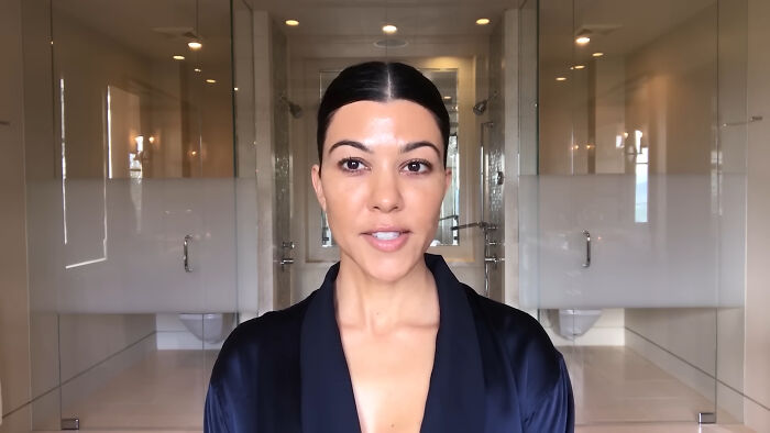Woman with dark hair in a sleek robe speaking in a modern bathroom, related to celebrity homes break-in stories.