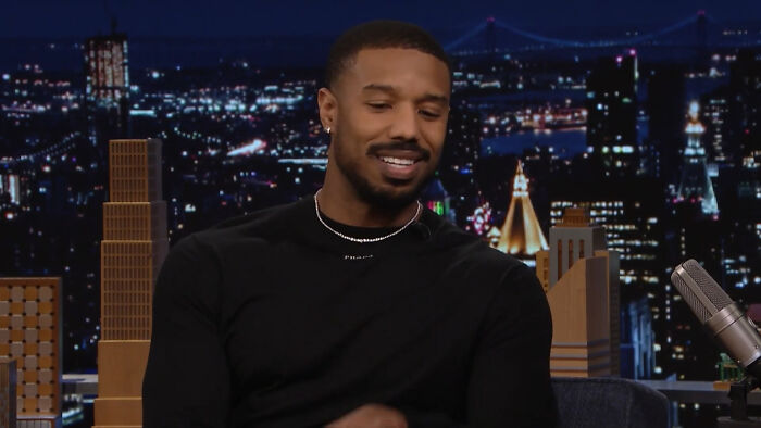 Actor Michael B. Jordan smiling during a late night talk show interview about celebrity homes break-ins.