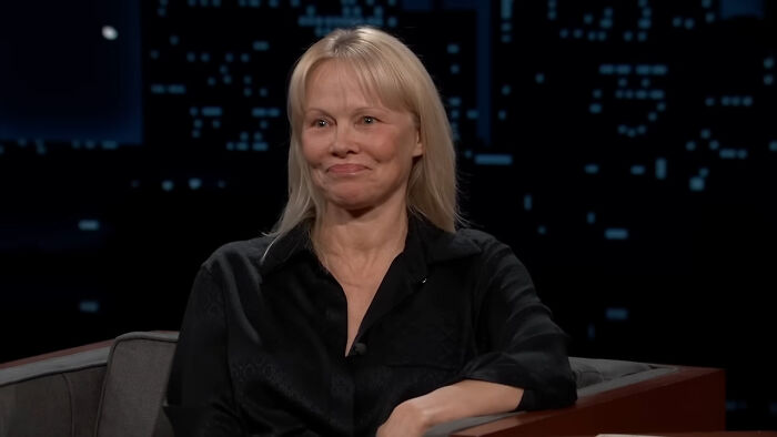 A woman in a black shirt sitting on a couch during an interview, related to celebrity homes broken into incidents.