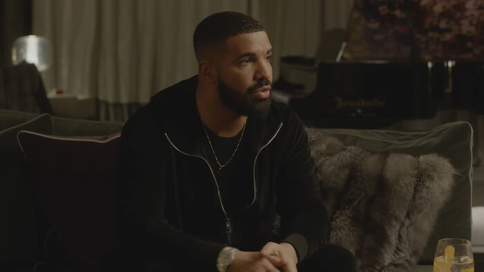 Man with a beard sitting on a couch in a dark room, related to celebrity homes broken into stories.