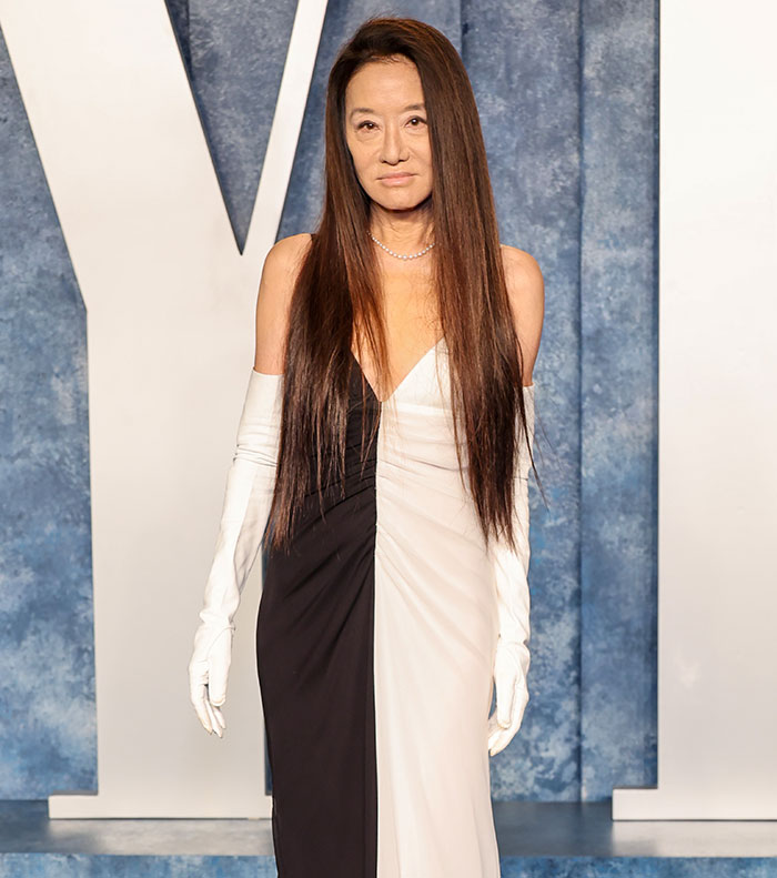 A woman in a black and white gown with long gloves, showcasing red carpet fashion.
