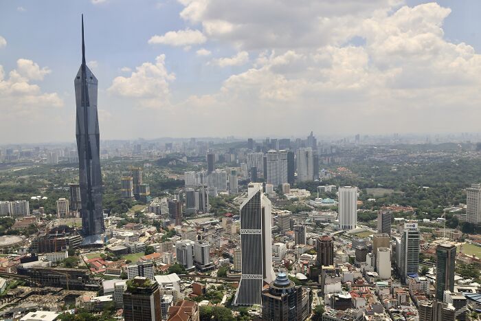 Aerial view of a cityscape featuring one of the world's tallest buildings under a partly cloudy sky.