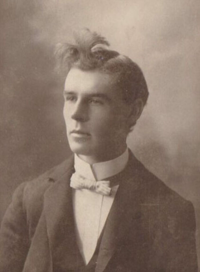 Vintage photo of a man with an unusual hairstyle, featuring an upward curl in formal attire.