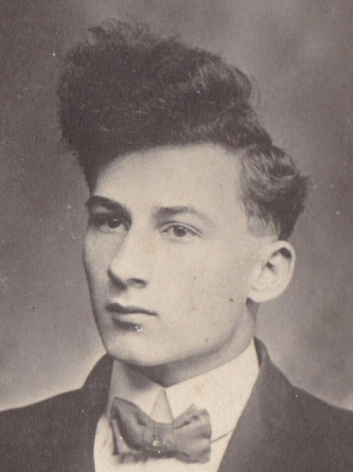 Retro hairstyle in a black and white photo, featuring a young man in a suit and bow tie from yesteryear.