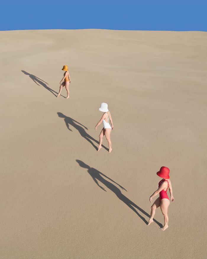 Aerial view of three women in swimsuits and hats walking on sand, casting long shadows; conceptual photography by Brad Walls.