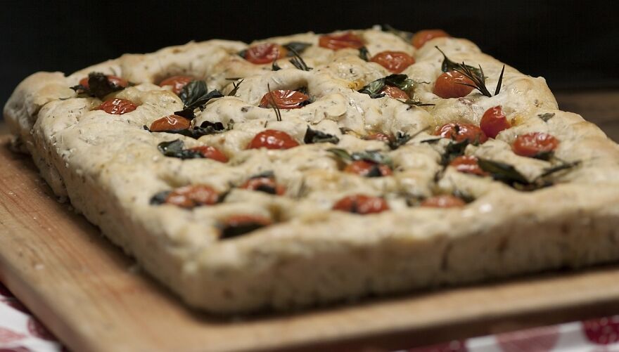 Freshly baked focaccia topped with cherry tomatoes and herbs, showcasing a delicious viral trend.