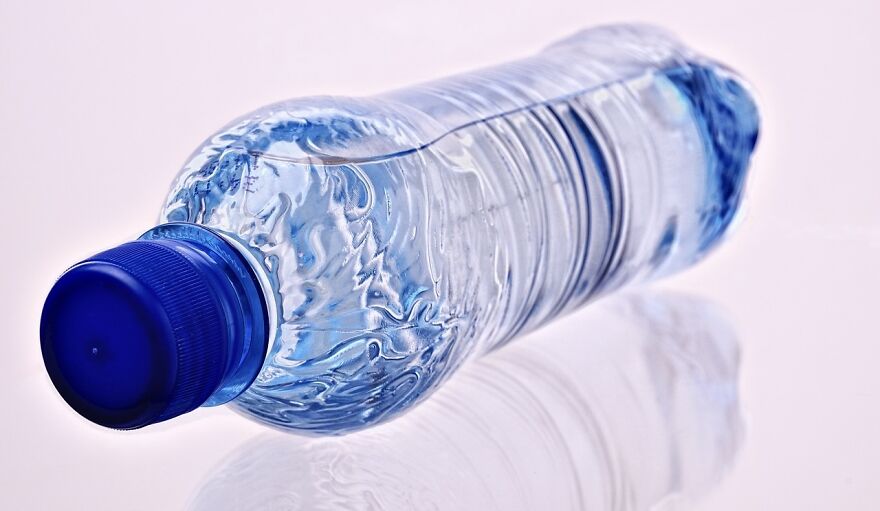 Plastic water bottle tilted on its side, highlighting its clear and textured design, related to trends.