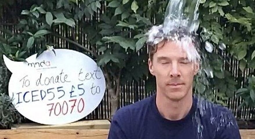 Person participating in the ice bucket challenge, a viral trend, with a donation sign in the background.