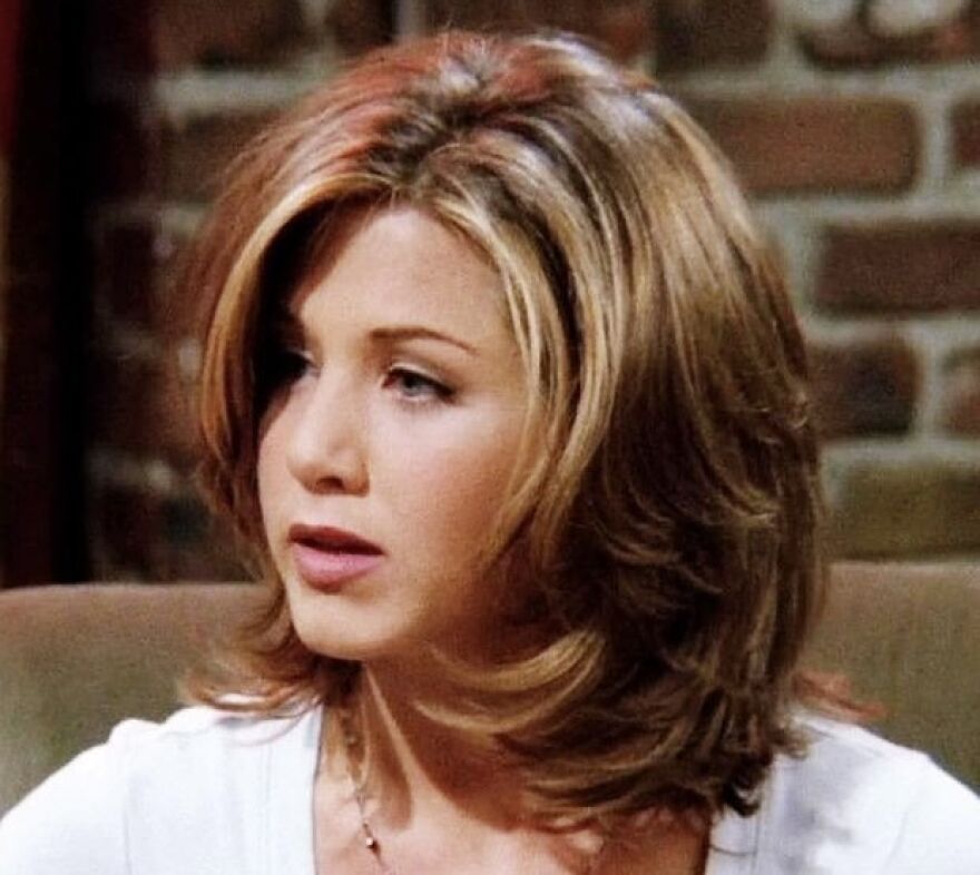 Person with layered hairstyle, a popular trend from the '90s, sitting indoors.