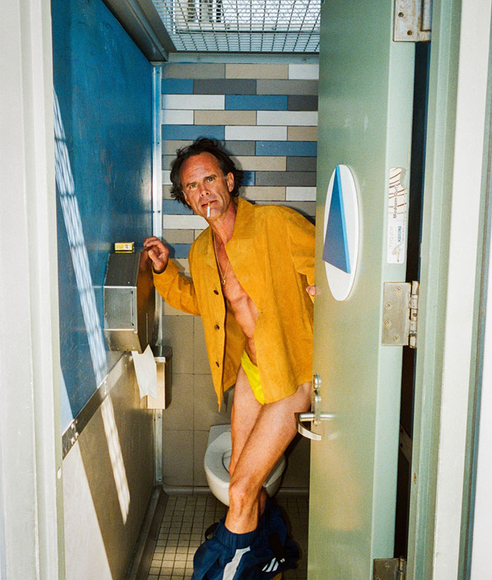 53YO in yellow outfit and open bathroom door, showcasing bold photoshoot style.