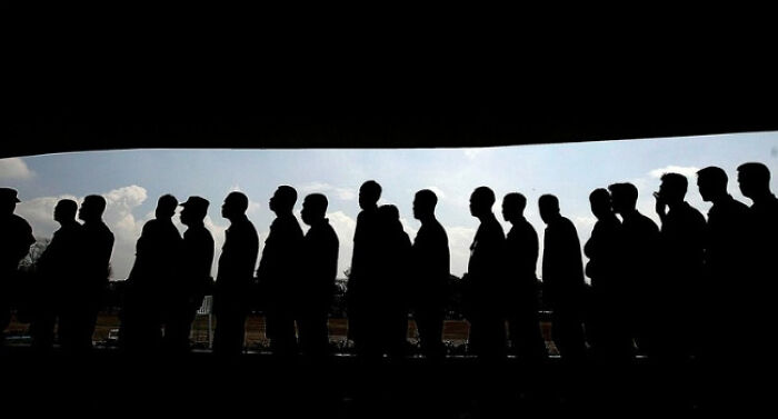 Silhouettes of people standing in line outdoors, representing a poll or survey about the struggles of adulting.