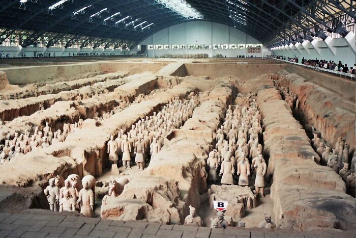 Ancient man-made structures featuring the Terracotta Army statues in an expansive protective hangar.