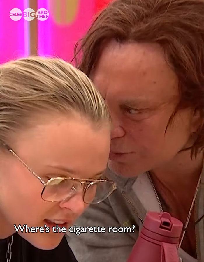 Two people conversing closely on 'Celebrity Big Brother', one holding a pink bottle.