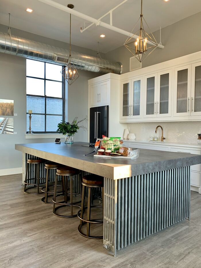 Stylish kitchen with a metal island and industrial design, but lacks practicality for home use.