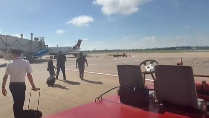 Passengers walk on tarmac near Delta jet after storm reroutes flights. Passengers walk on tarmac near Delta jet after storm reroutes flights.