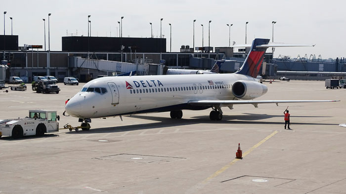 Delta plane at airport tarmac after rerouting due to storms, highlighting passenger delays. Delta plane at airport tarmac after rerouting due to storms, highlighting passenger delays.