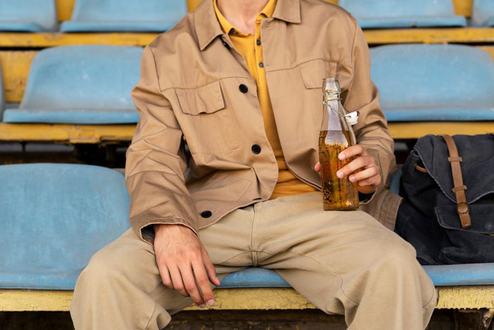 Person seated holding a bottle, representing foods and drinks to avoid at the airport.
