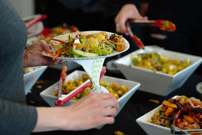 Person holding a plate of assorted foods at a buffet, highlighting choices to avoid consuming at the airport.