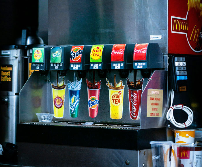 Airport soda machine with various drink options, showcasing beverages to consider avoiding as per nutritionist advice.