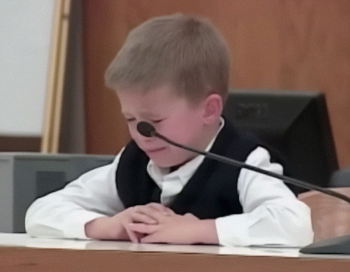 A child in a courtroom, appearing upset during testimony related to his mother's life sentence.