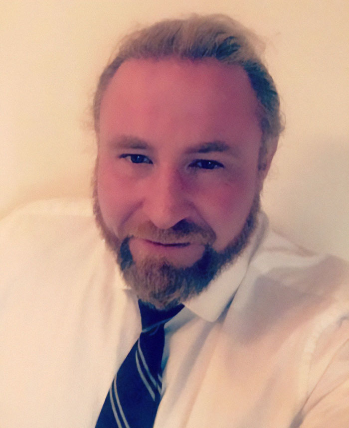 A man in white shirt and tie smiling, related to a family's burial mystery.