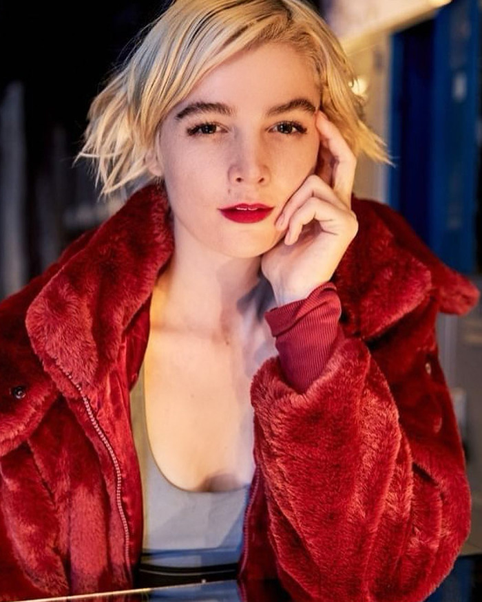 Blonde woman in a red coat, posing thoughtfully, related to allegations against Jared Leto.