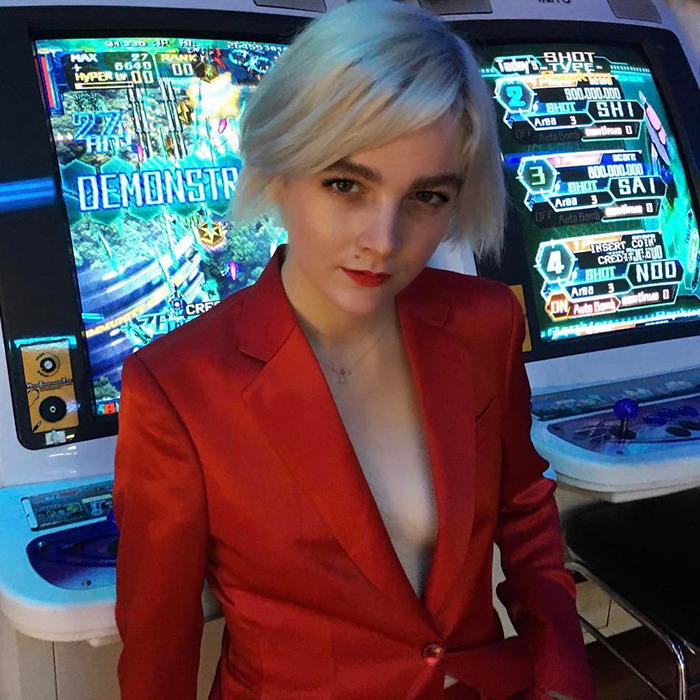 Person in a red suit stands confidently in front of a gaming machine.