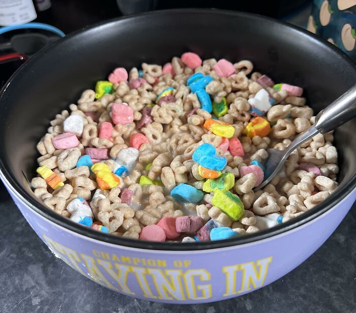 A bowl of colorful American breakfast cereal with marshmallows and a spoon.
