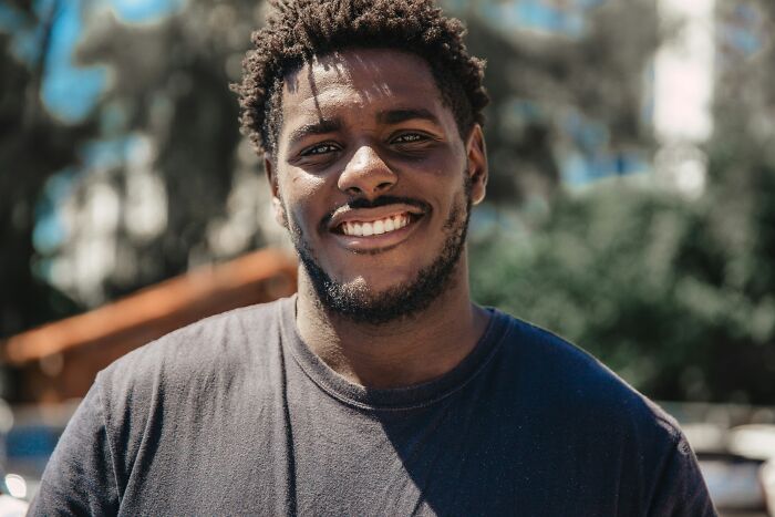Smiling man outdoors in a dark shirt, capturing the essence of an American tourist.