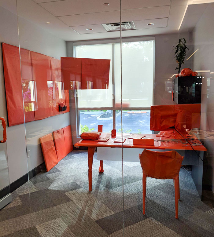 Office prank with everything covered in orange wrap, showcasing a coworker's humor.