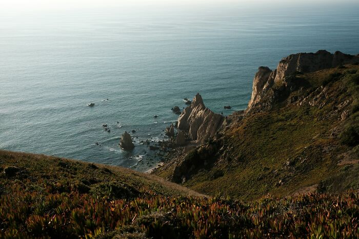 Coastal cliffs and ocean view at a popular island, highlighting overcrowding issues from the wealthy.