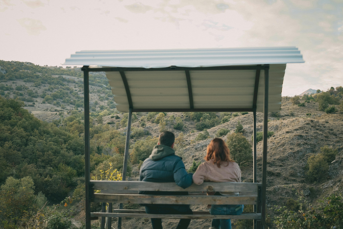 Couple sitting together on a bench under a shelter, overlooking a landscape, relating to a failed April Fools' prank. Couple sitting together on a bench under a shelter, overlooking a landscape, relating to a failed April Fools' prank.