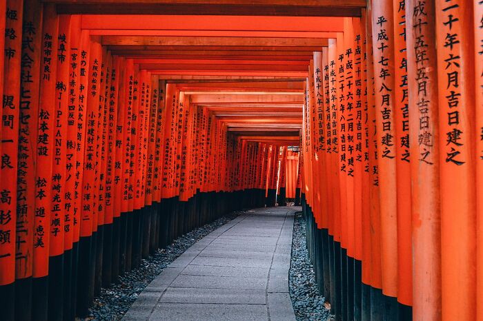 Pathway through vibrant red gates at Fushimi Inari Shrine, a famous tourist spot.
