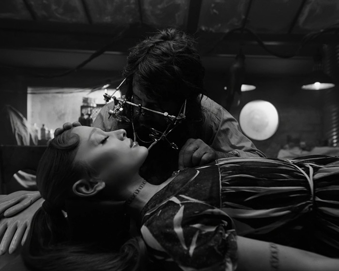 Ariana Grande shown with tattoos and hair transformation in a dramatic black-and-white setting.