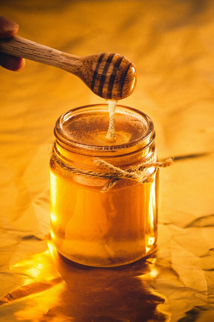 Jar of honey with a honey dipper dripping liquid honey, illustrating obvious things you've just become aware of concept.