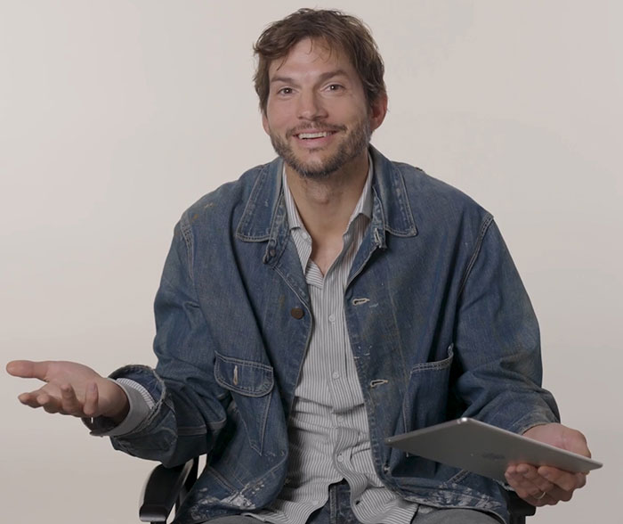 Man in denim jacket gesturing, holding a tablet.