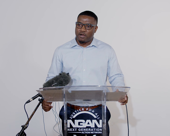 Man speaking at a podium with NGAN logo, addressing Austin Metcalf conspiracy theory. Man speaking at a podium with NGAN logo, addressing Austin Metcalf conspiracy theory.