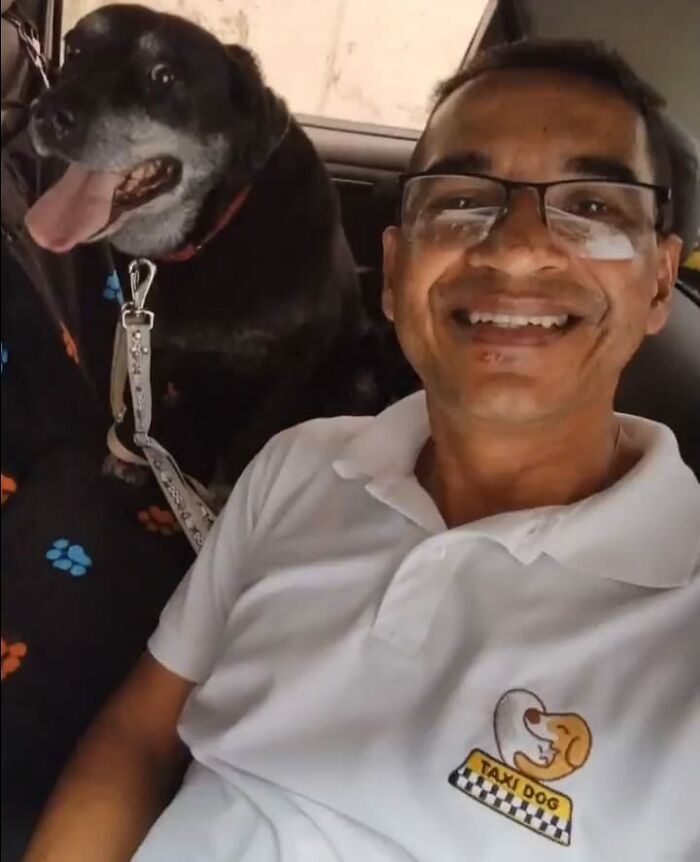 Man taking a selfie with a happy dog in his pet taxi, both smiling and enjoying the ride.