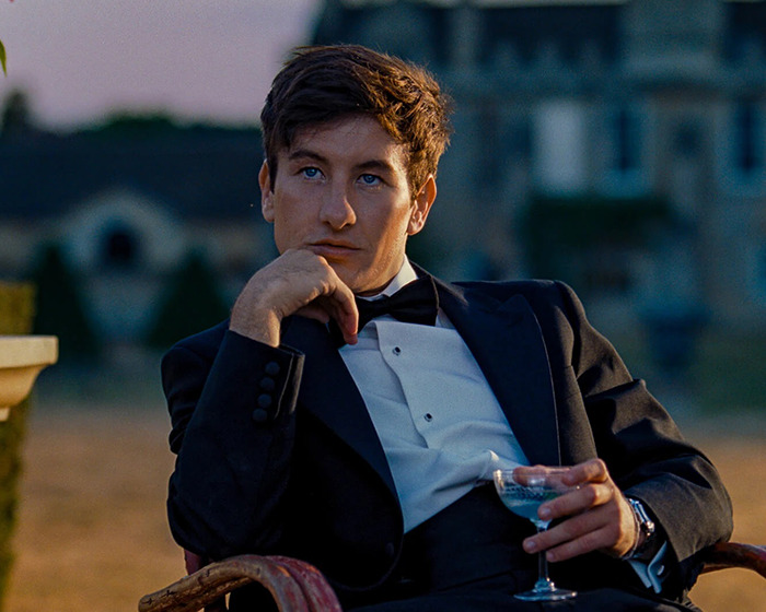 Man in formal attire sitting outdoors, raising questions about casting choices in Beatles biopic.