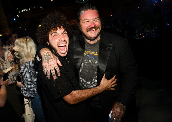 Two men including Benny Blanco smiling and embracing at a nighttime event, showcasing Benny Blanco's vibrant presence and success.