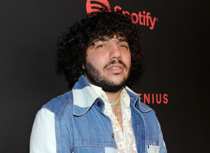 Benny Blanco in a denim jacket with a curly hairstyle at a Spotify event, related to net worth and music industry success.