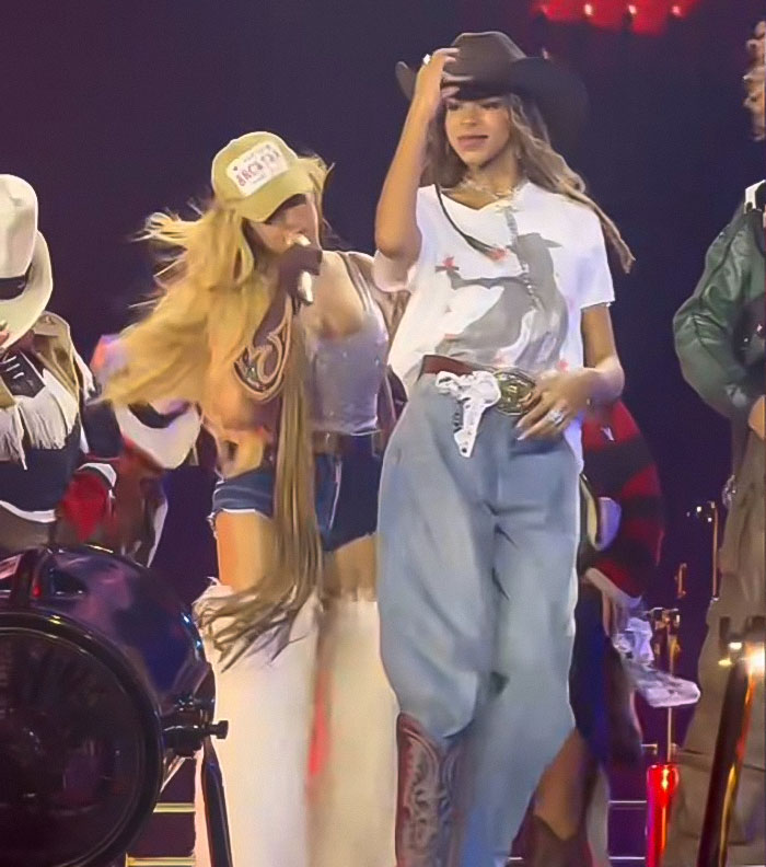 Beyonc&eacute; and Blue Ivy performing live on stage with blue jeans and cowboy hats in a dynamic concert setting.