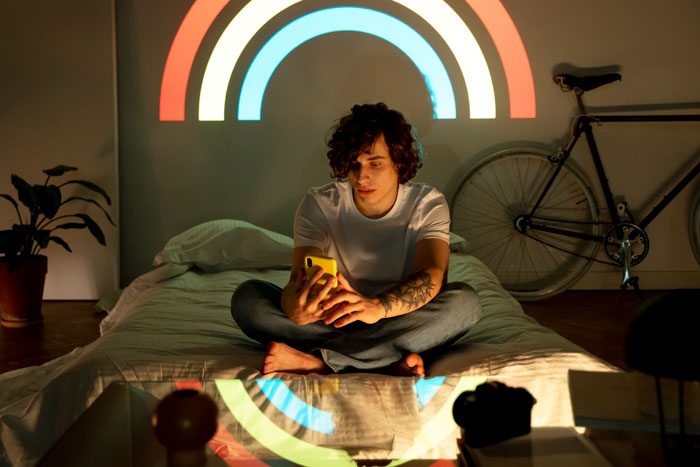 Young person sitting on bed using phone, dealing with lack of proper sleep caused by boyfriend for three weeks Young person sitting on bed using phone, dealing with lack of proper sleep caused by boyfriend for three weeks