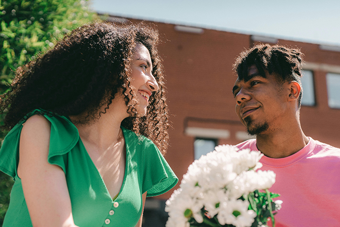 Ex-girlfriend smiling at boyfriend with flowers, outdoors. Ex-girlfriend smiling at boyfriend with flowers, outdoors.