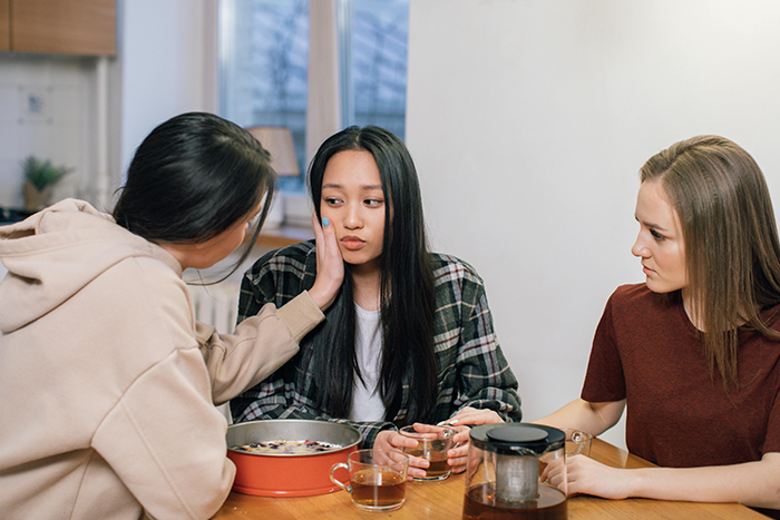 Three women at a table, one consoling an upset ex-girlfriend over a marriage issue. Three women at a table, one consoling an upset ex-girlfriend over a marriage issue.