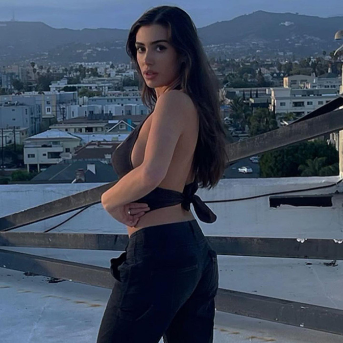 Bianca Censori poses on a rooftop at dusk, wearing a black halter top and jeans, creating a buzz after Kanye West split.