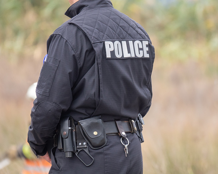 Police officer in uniform outdoors, with "POLICE" visible on the back.
