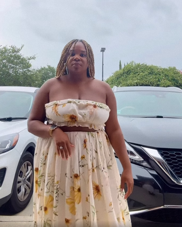 Woman in floral dress outside, related to lawsuit against restaurant over outfit being considered too revealing.